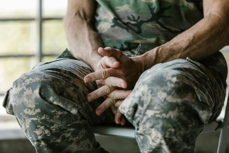 a soldier holding his hands together and sitting in a chair