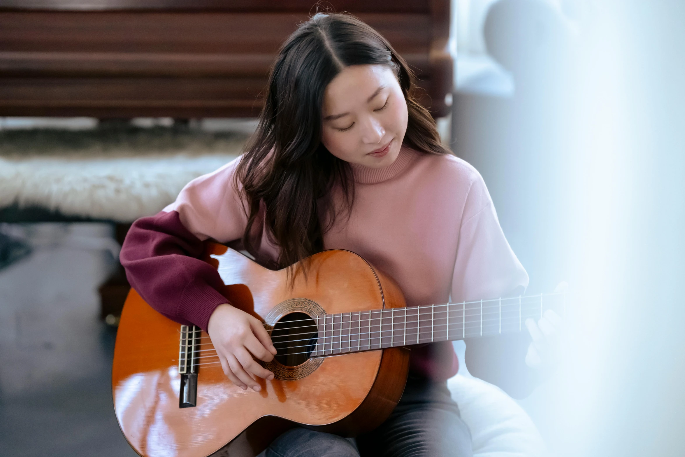 a girl sitting with her head down on the ground playing a guitar