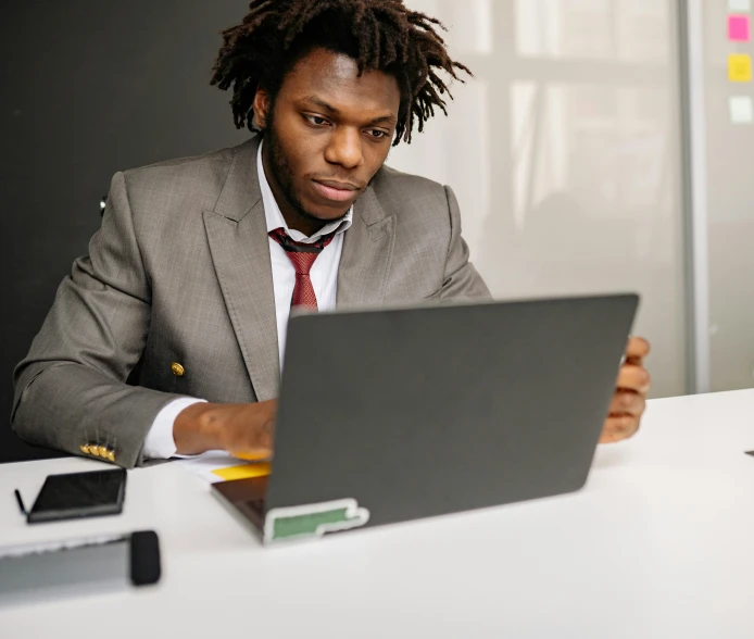 a man sitting at a table looking at his laptop