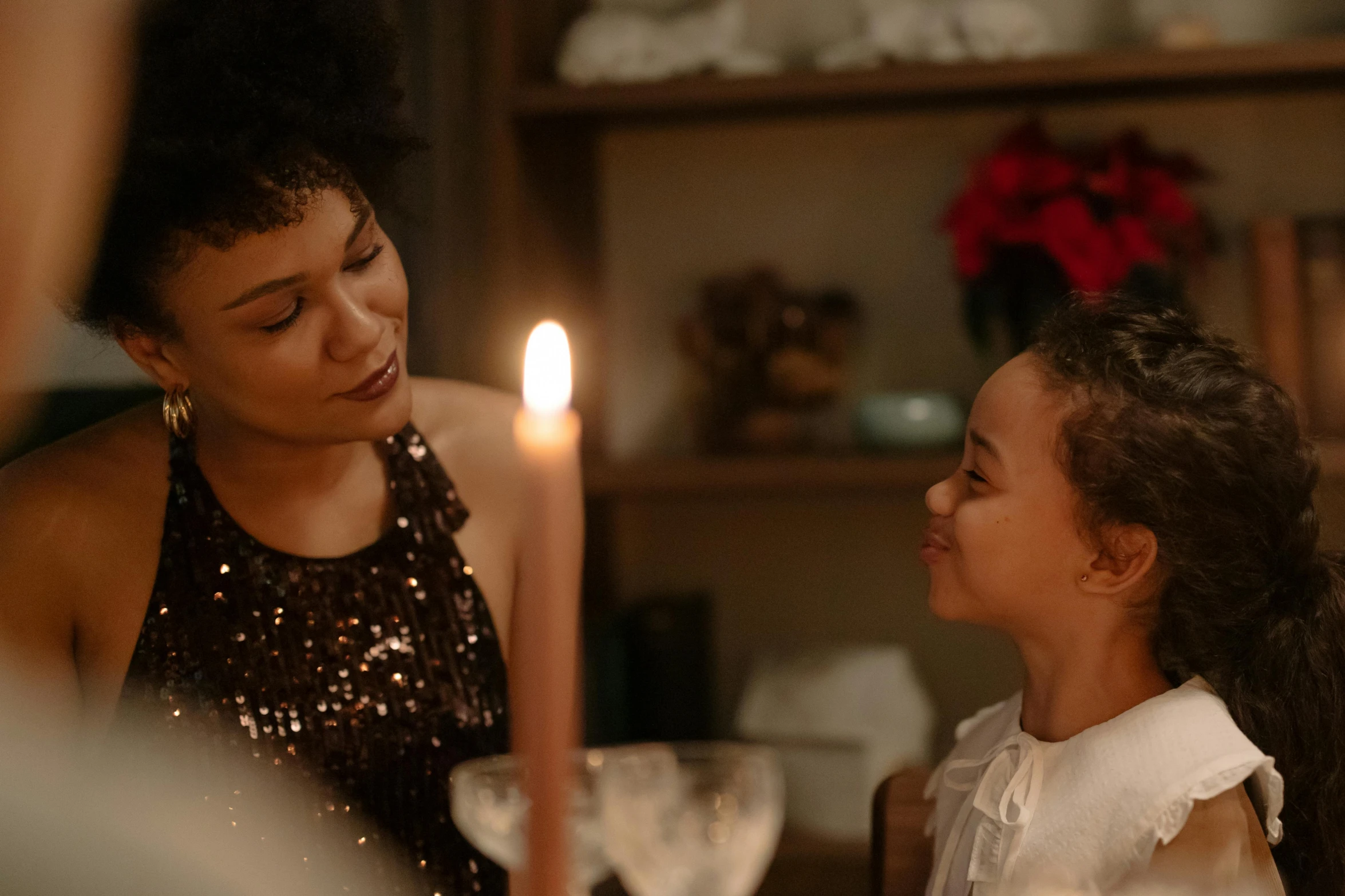 a woman looking at a child while she sits in front of a candle