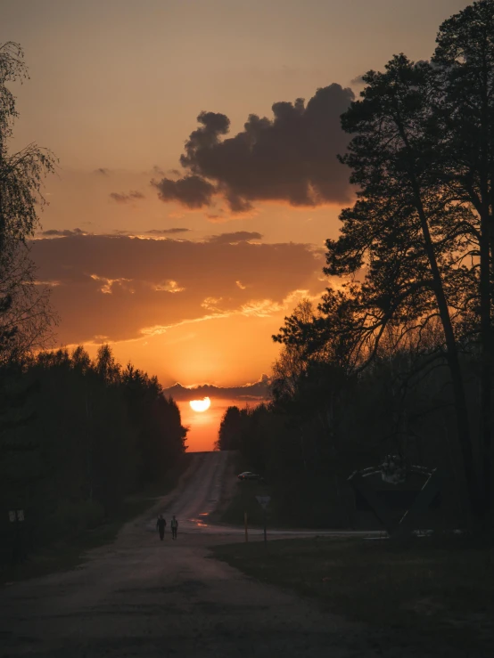 two people walking down the road during sunset