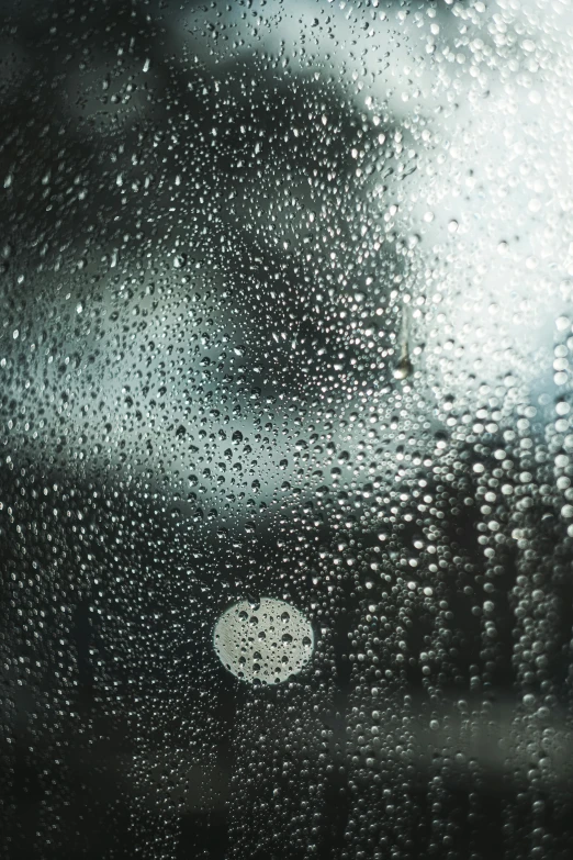 rain drops fall on the window glass in a darkened setting