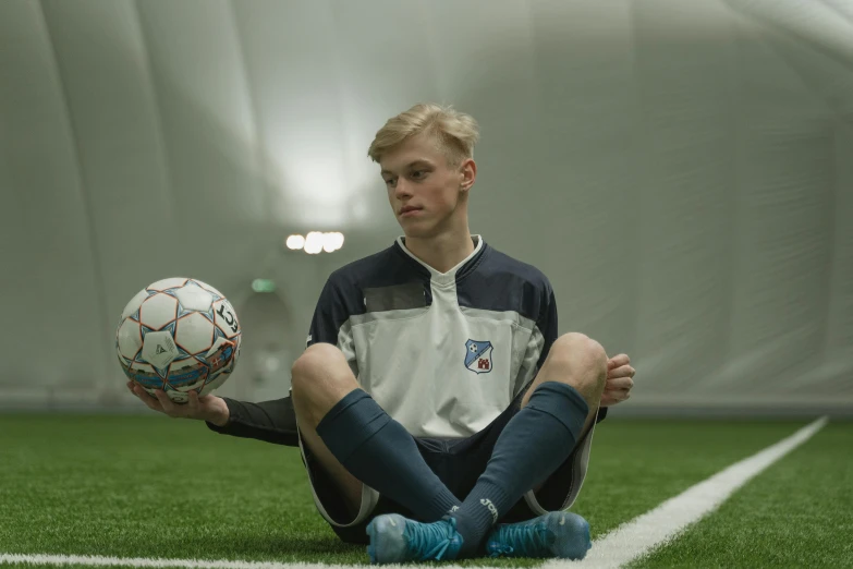 the young man is holding the soccer ball in his hands