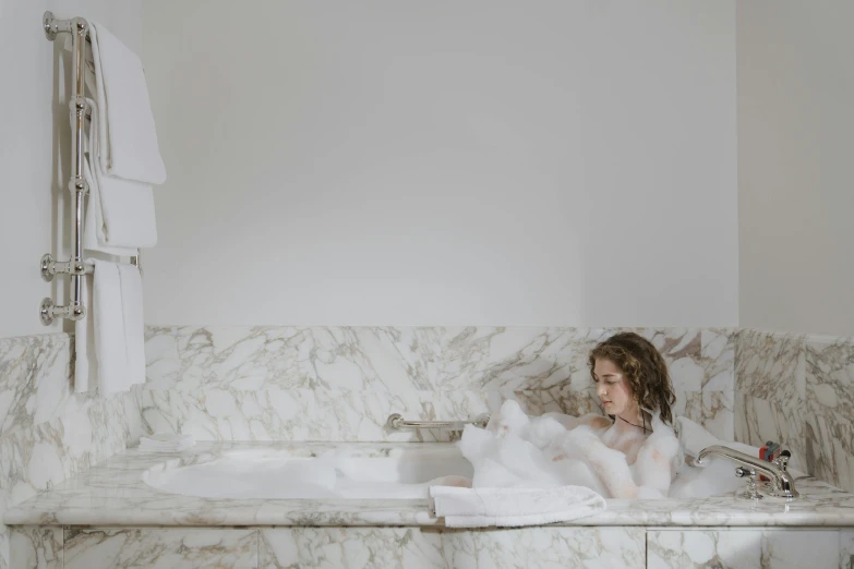 a little girl with long hair sitting in a bathtub