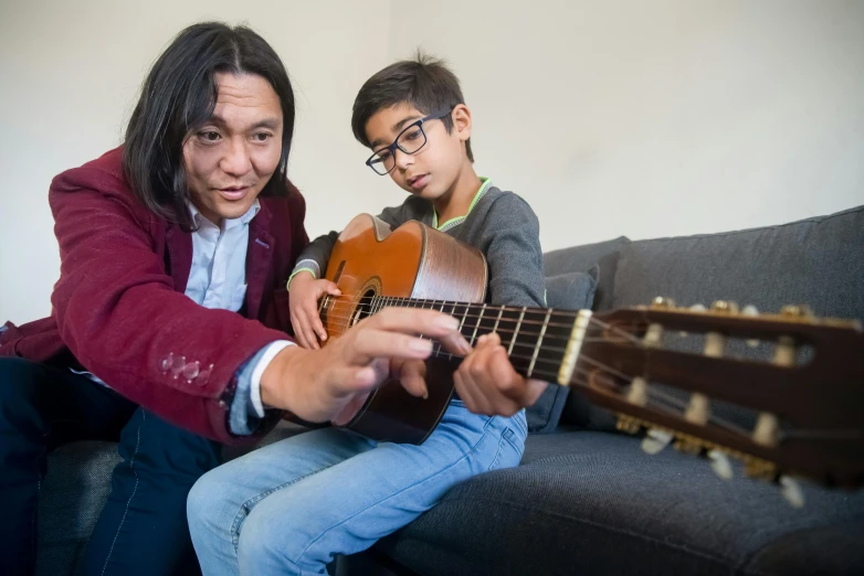 the man is playing the guitar with the little boy