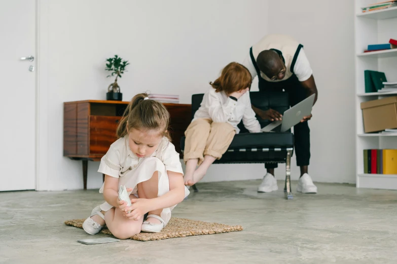 a small girl in a white shirt sits on the ground with a brush