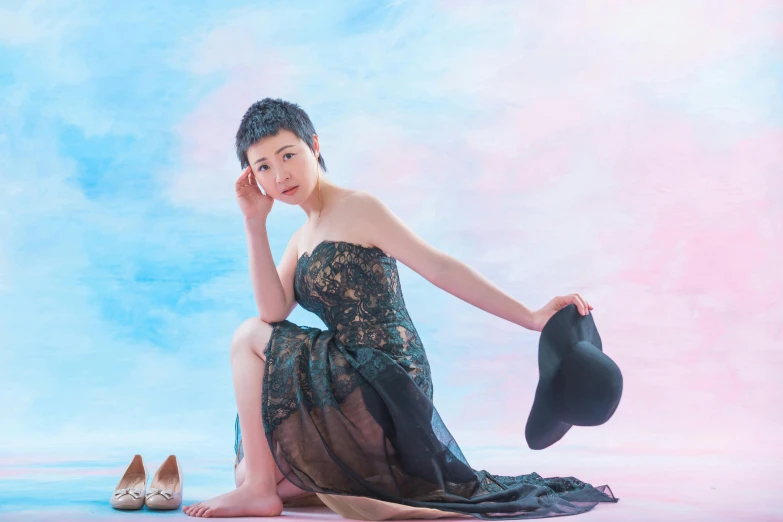 a woman sits on the floor while wearing a black dress