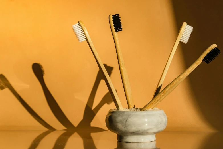 a few tooth brushes sit in a vase