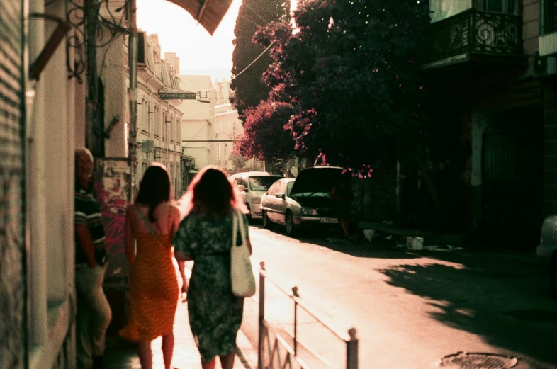 some women standing near one another and one is walking