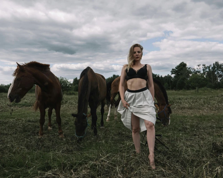 woman wearing black top and white skirt standing next to horses