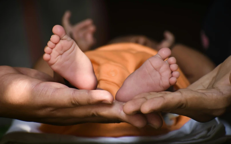 a baby has his foot in another persons hands