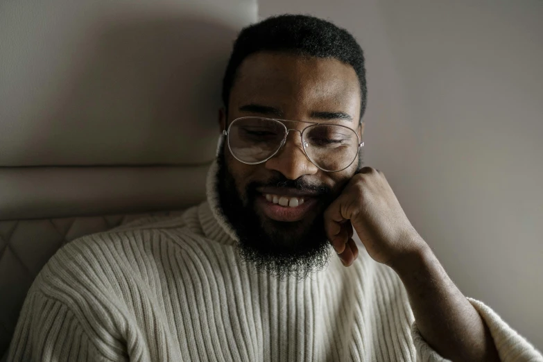 a man with glasses smiling while looking at a cell phone