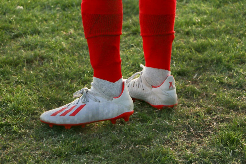 a soccer player wearing red socks stands on grass