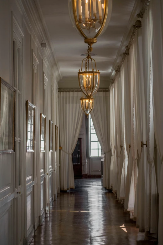 a room with several white curtains and a chandelier