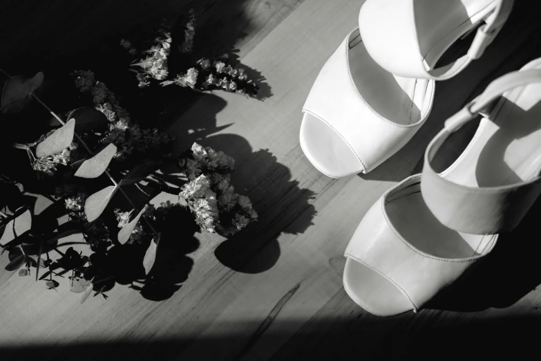 black and white pograph of wedding shoes and flowers