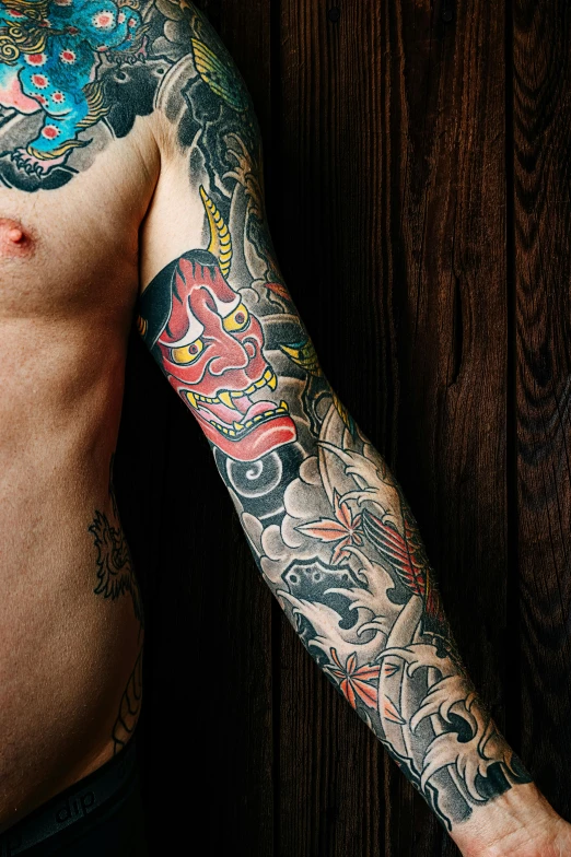 a man with many tattoos stands by the wall
