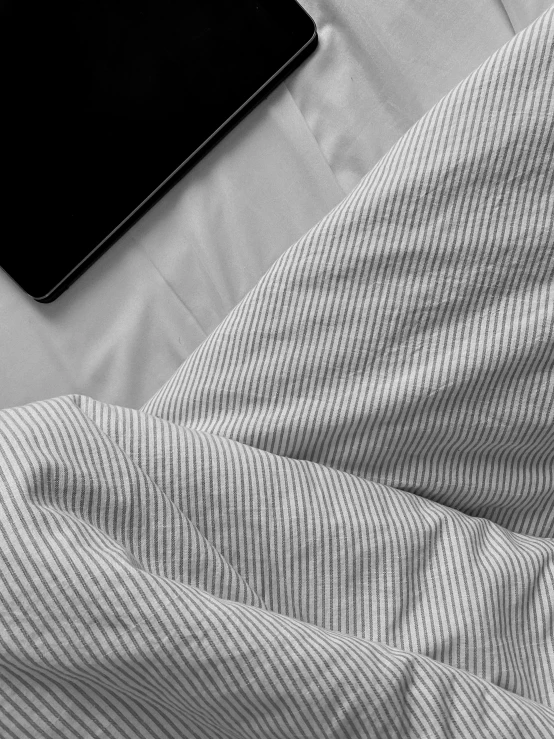 an overhead view of a white sheets with the bedding and a book on top of them