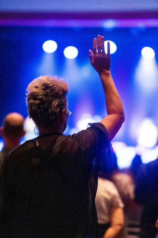 a person standing in front of a large crowd with their hands up