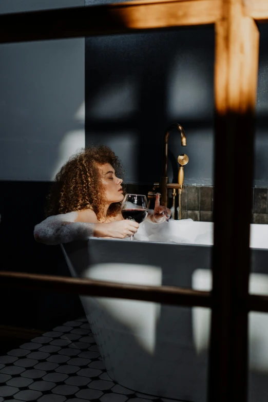 a woman in a bathtub looking at the water pouring