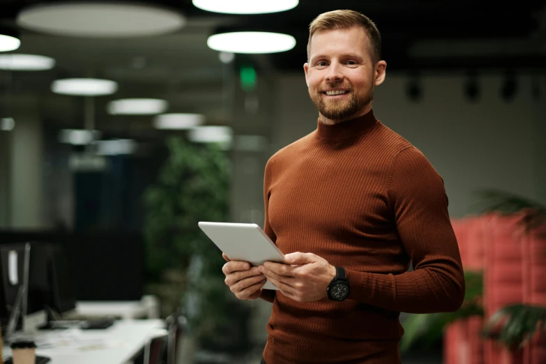 a man standing in front of laptops and holding a tablet