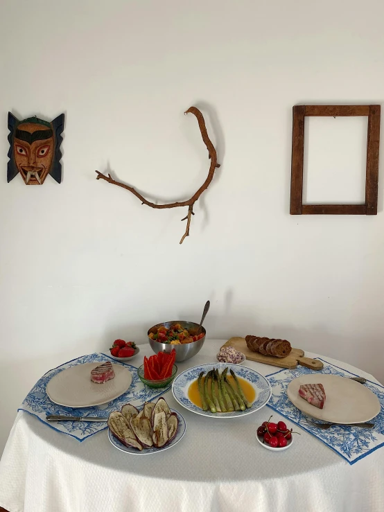 bowls on the table with a bowl of fruit and a nch hanging on the wall