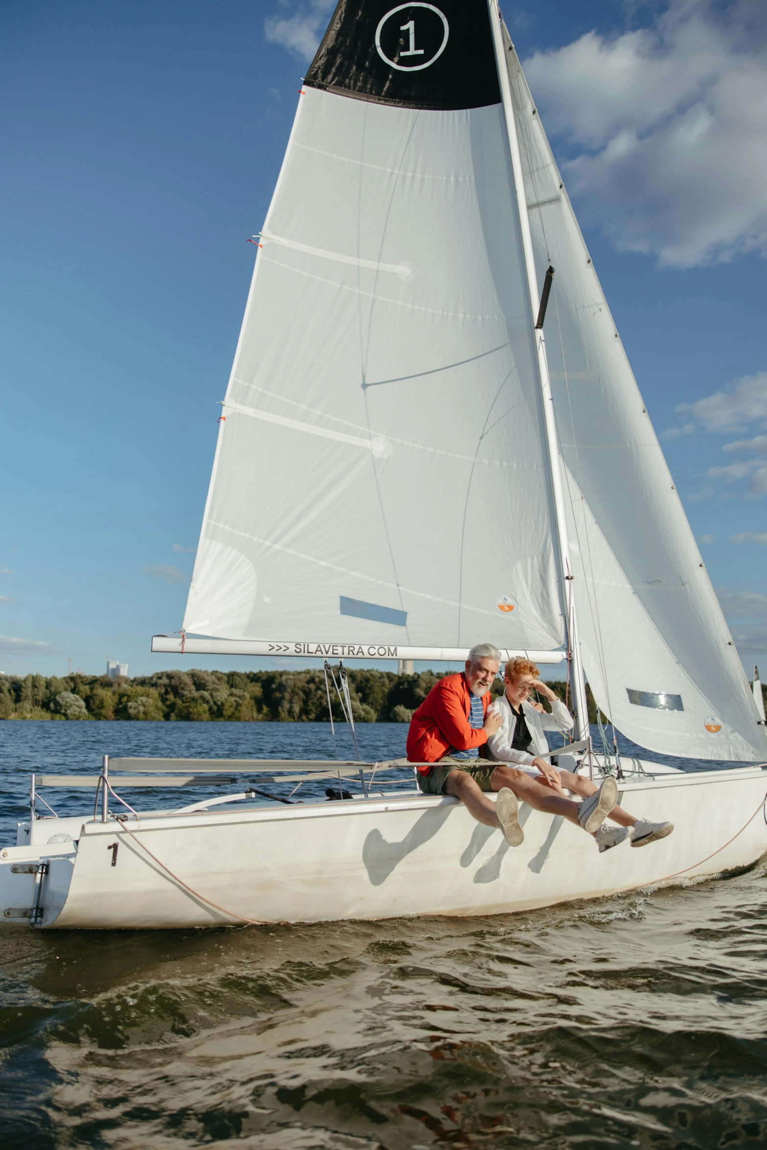 two people in an orange life jacket are sitting on a white boat on the water