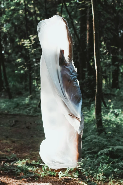 the woman is walking through the woods in her flowing clothing