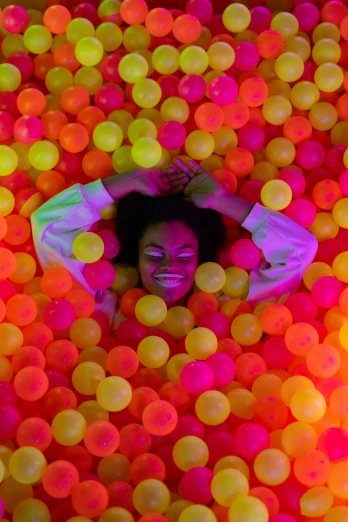 a woman in pink and green has her head above a surface filled with balls