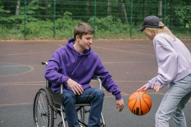 a woman hing a man in a wheelchair while holding a basketball