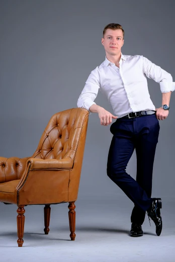 a man standing next to an old leather chair