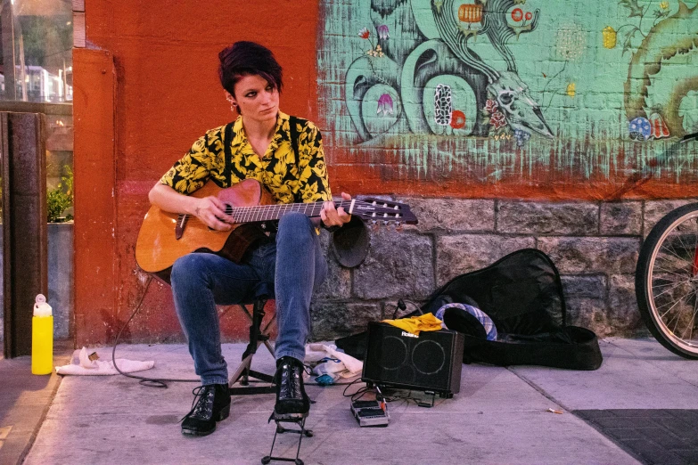 a man in yellow is playing an acoustic guitar