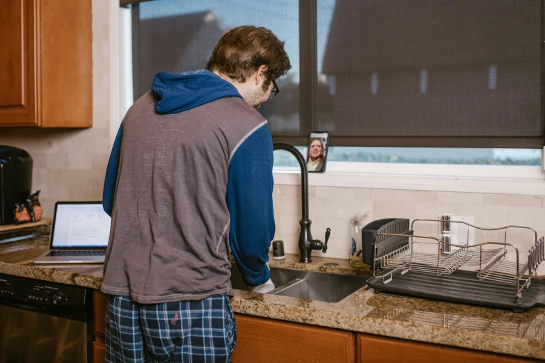 the man is at a kitchen sink preparing food