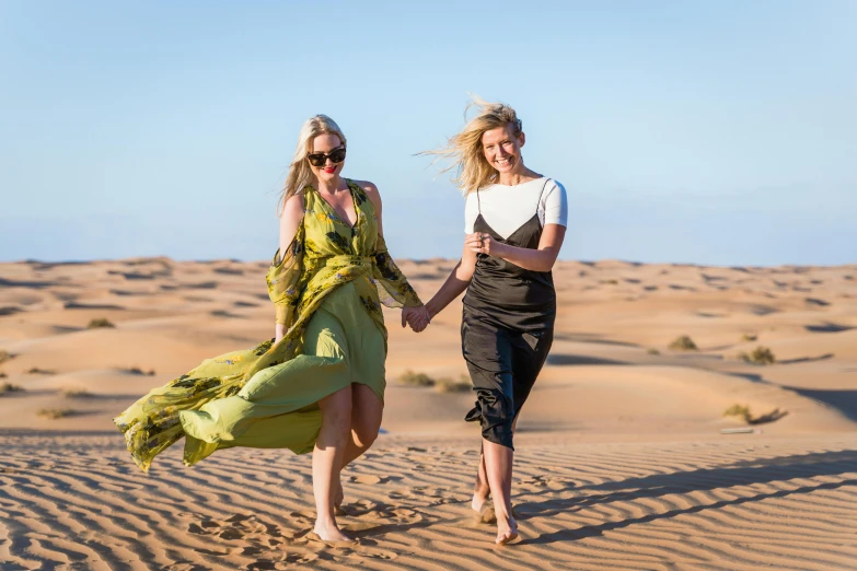 two young women walk along an open desert