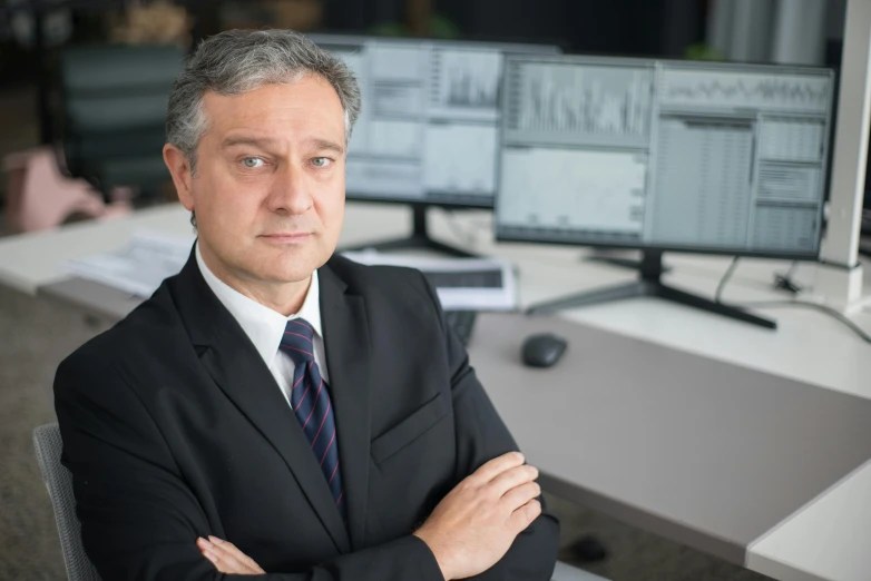 a man in suit and tie standing in front of a desk