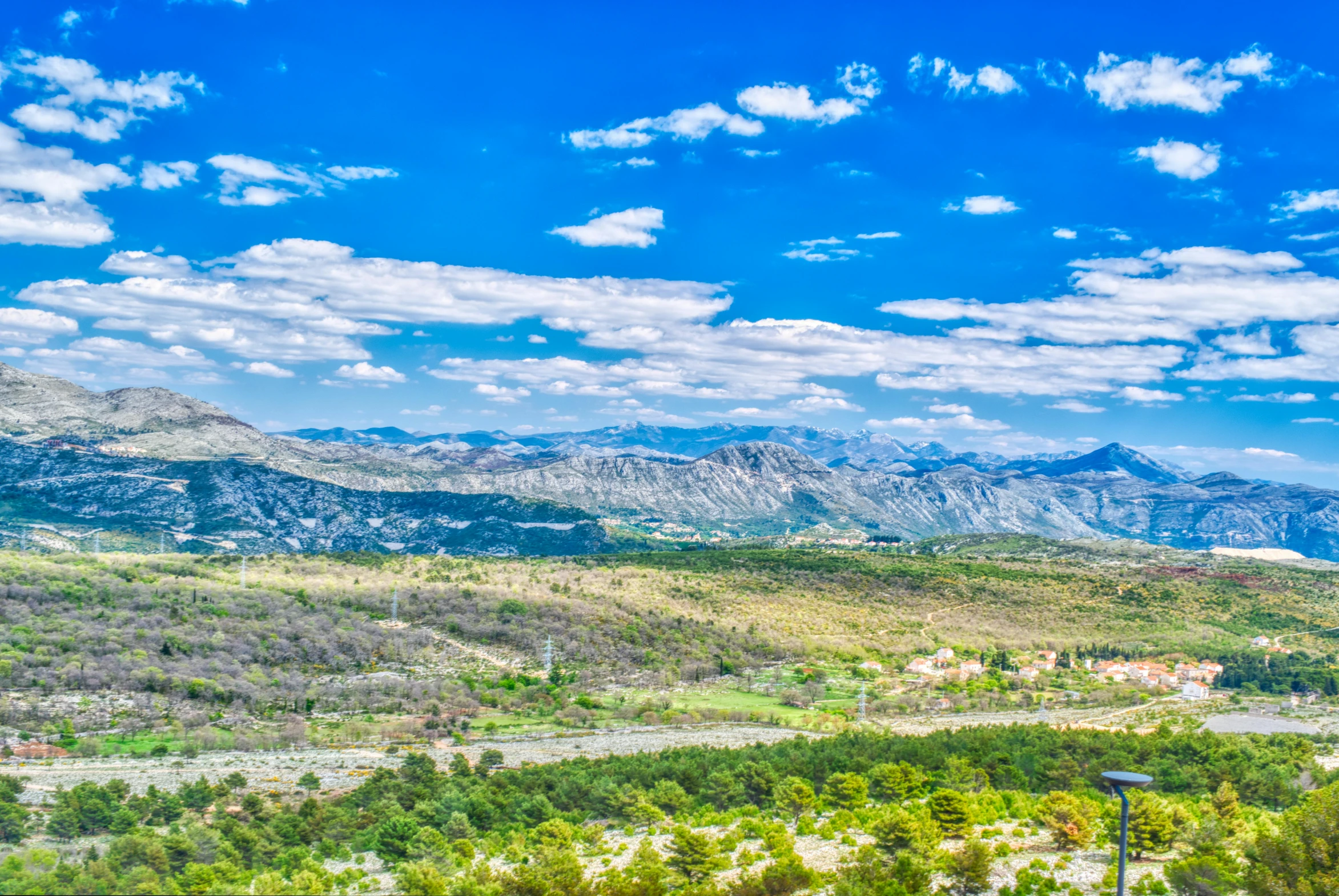 the view of a lush green hillside below mountains