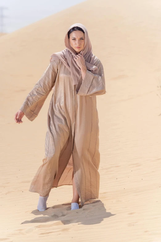 a woman is walking in the sand wearing a dress