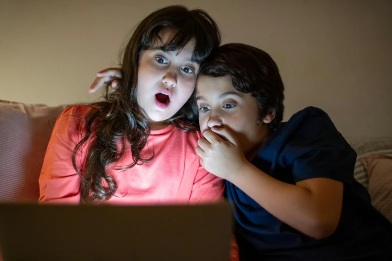 two children are watching soing on a laptop