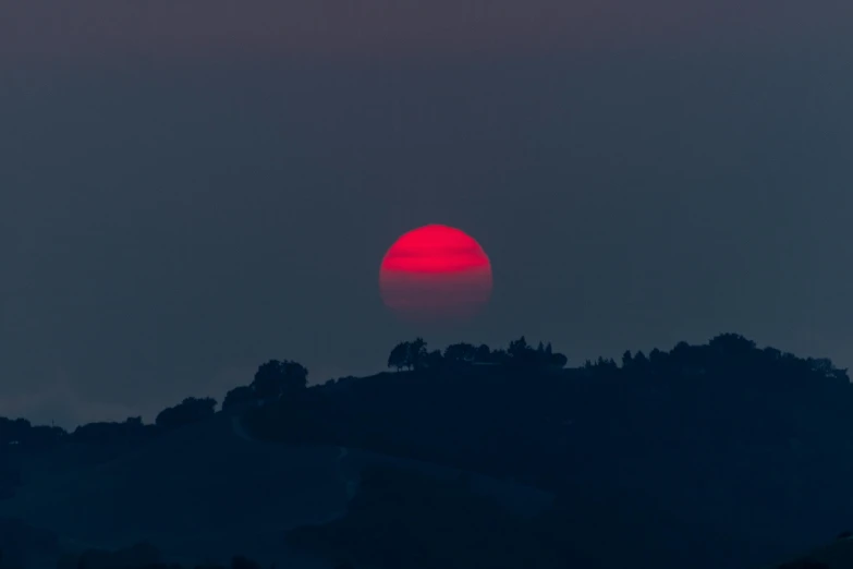 a red ball is in the sky with some trees