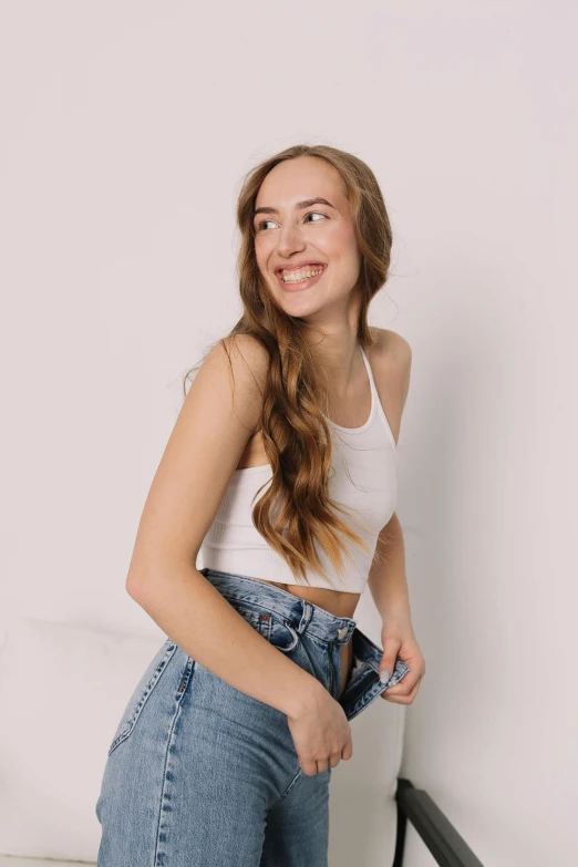 a smiling  in high waist jeans with her arm around the thigh