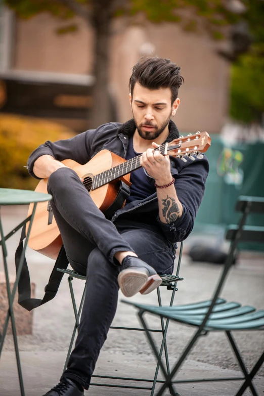 a man is sitting in a chair playing the guitar