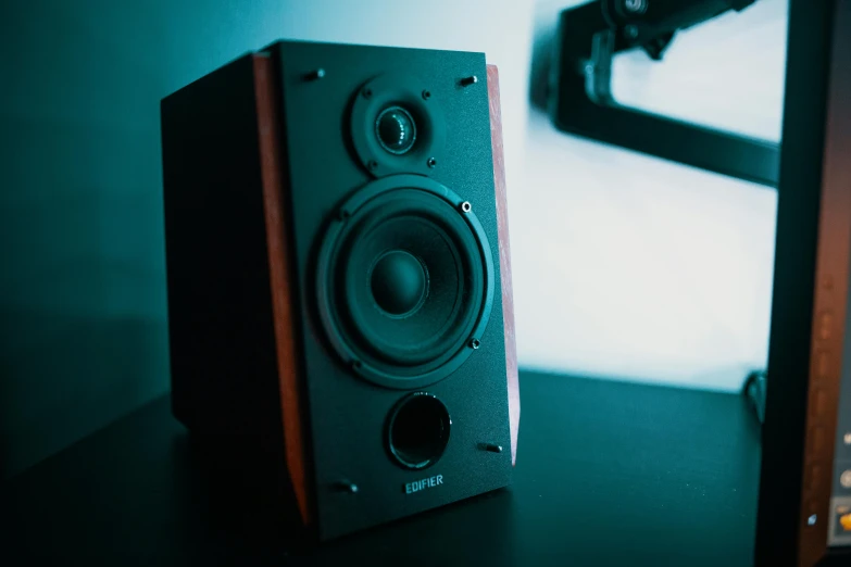 a stereo receiver on a wooden table next to a speaker