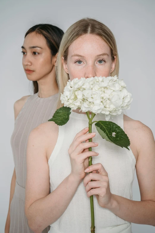 two beautiful women with flower heads over their faces