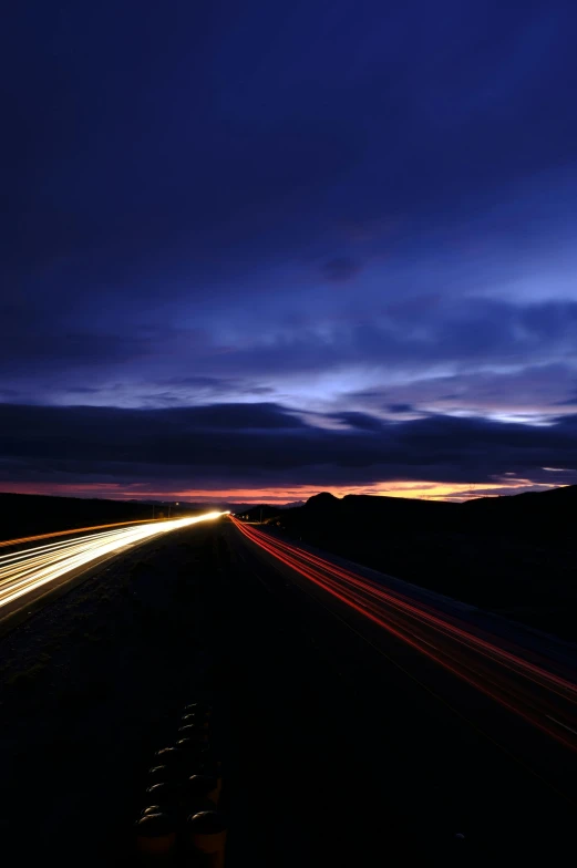 the night time light streaks are glowing on a dark road