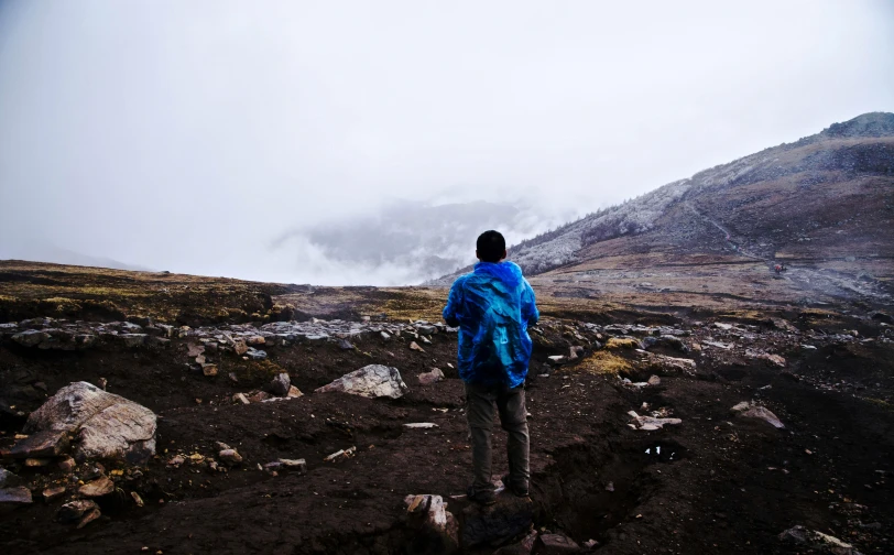 a person in a raincoat walking up a mountain