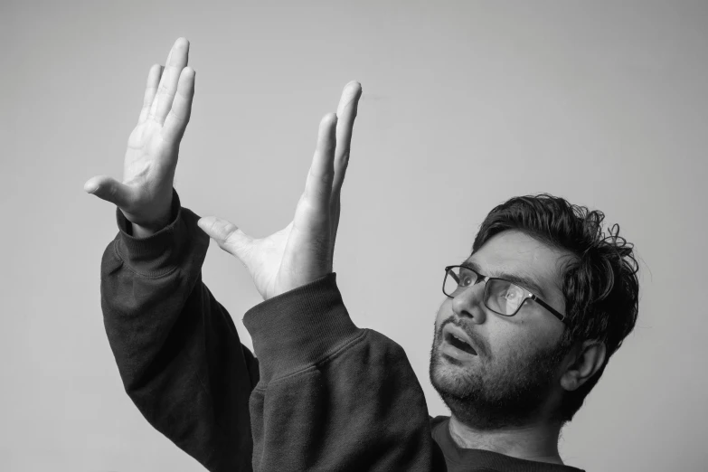 a young man is making hand signals while wearing glasses