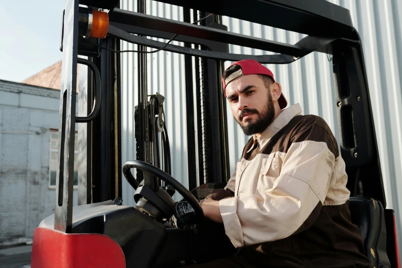 a man wearing a red hat sitting on top of a forklift