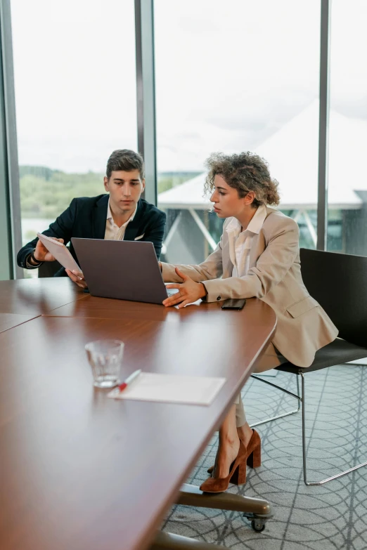 two people are sitting at a table on laptop computers