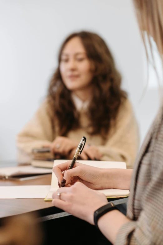 two girls are sitting at a table with a notebook