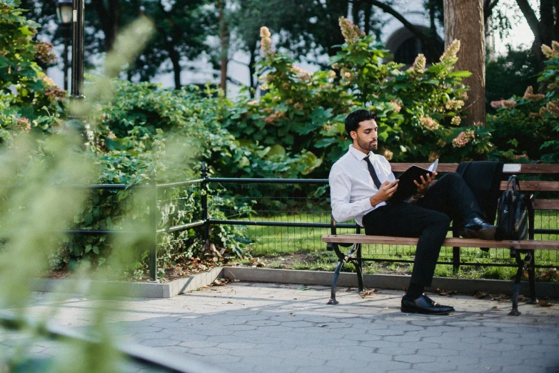 man in white shirt sitting on wooden bench in park