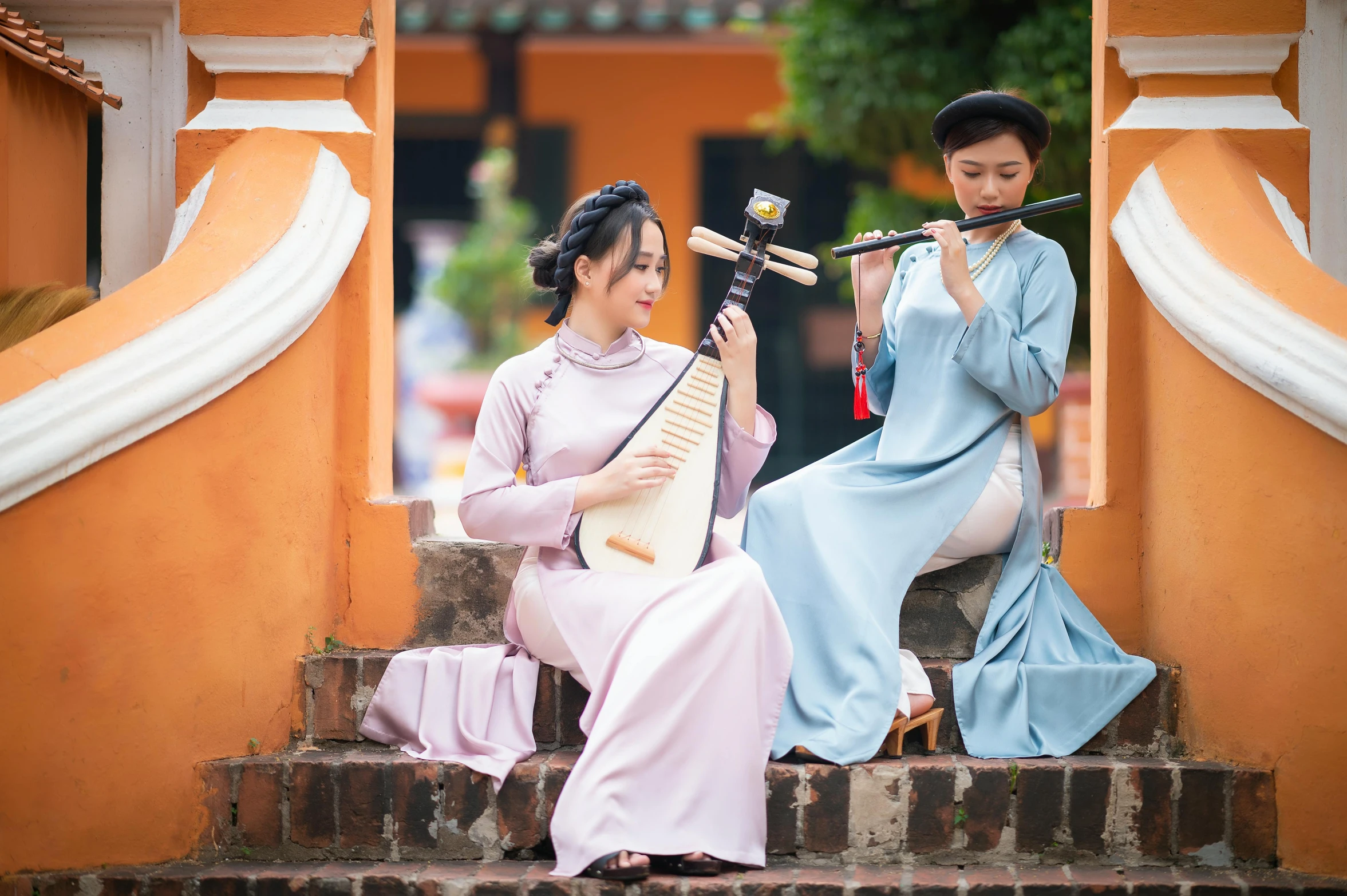 two young women with instruments sit on the steps